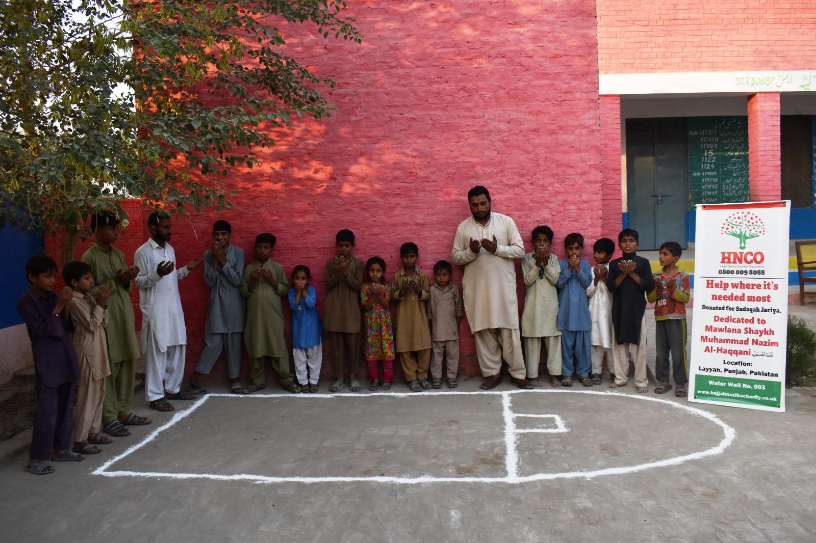 Community praying beside HNCO water well site in Layyah, Punjab