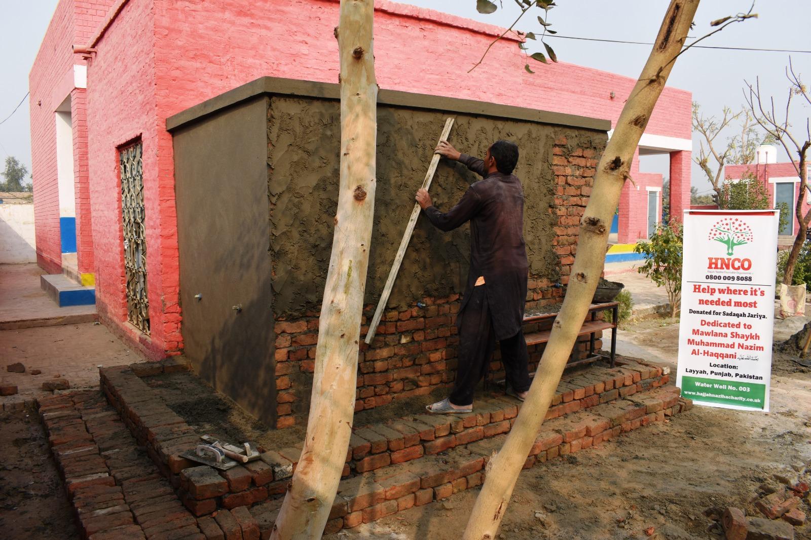 Builder constructing pump house for HNCO water well project